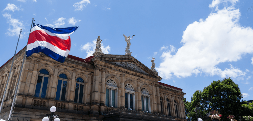 Costa Rican flag in front of a historic theater building under a blue sky