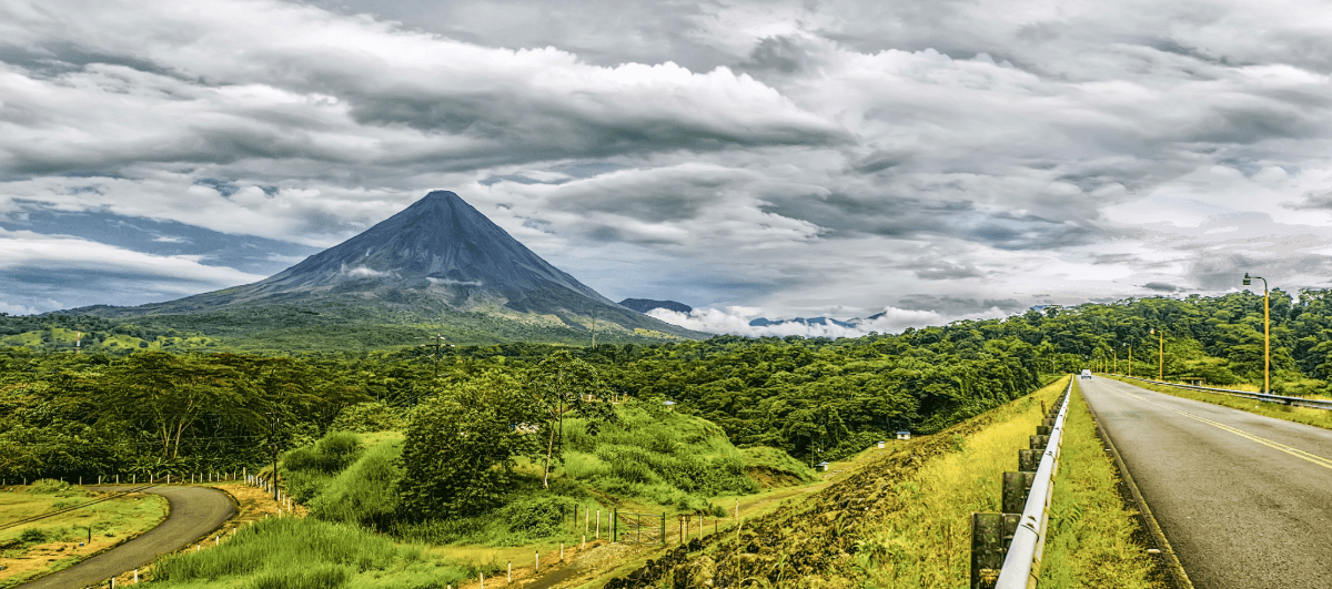 Volcano in Costa Rica with road, rainforest and cloudy sky