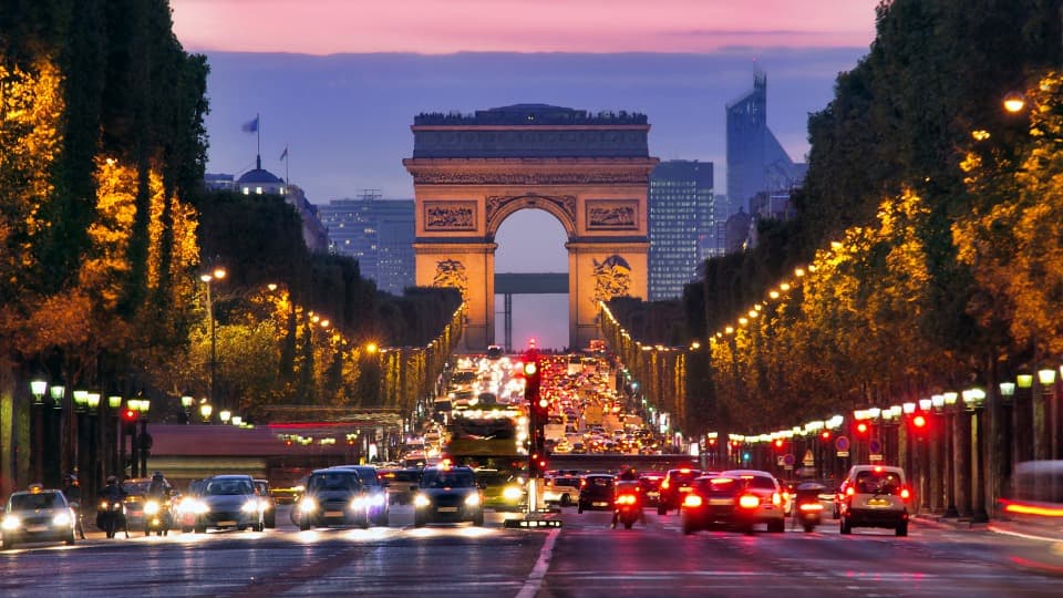 Arc de Triomphe in Paris at dusk with traffic on the Champs-Élysées