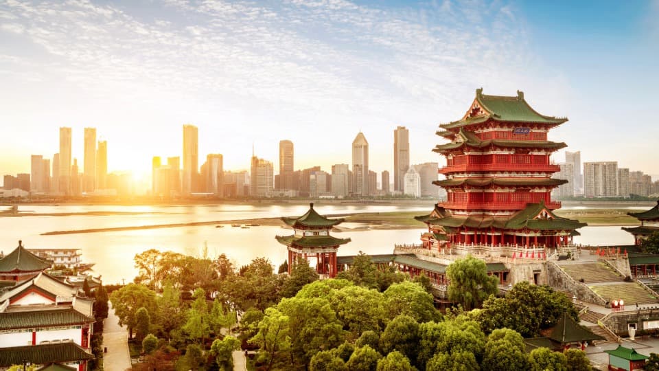 Aerial view of a historic city in China; in the background, a large, modern metropolis can be seen