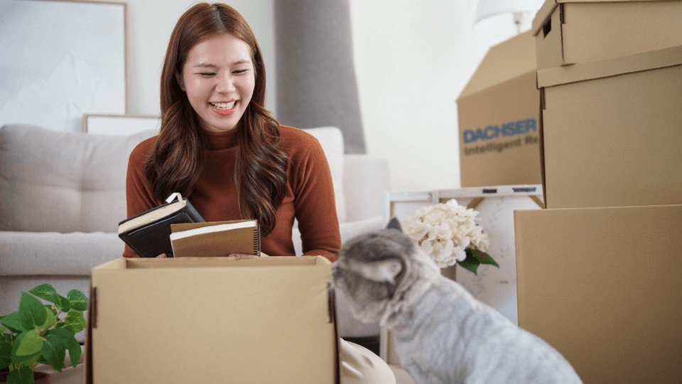 Woman packing moving box with cat – your pet relocation to Switzerland with DACHSER & KOLB.