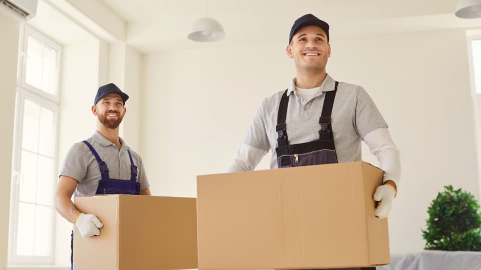 Two professional movers from DACHSER & KOLB handling a small shipment with moving boxes using two-man handling.