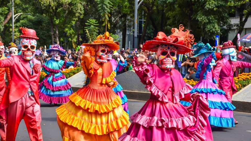 Costumed people wearing skull masks celebrate Día de Muertos in Mexico.