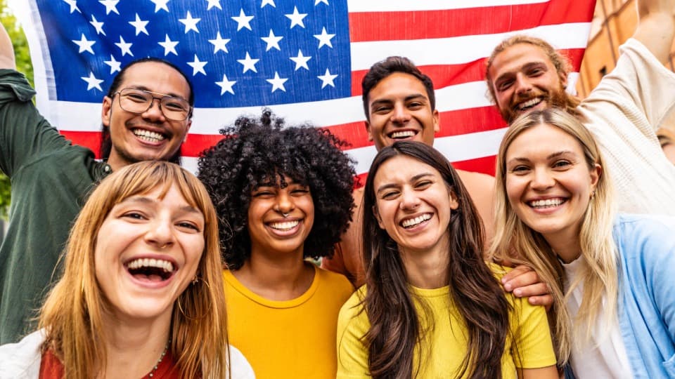 People from the United States smiling at the camera with a national flag.