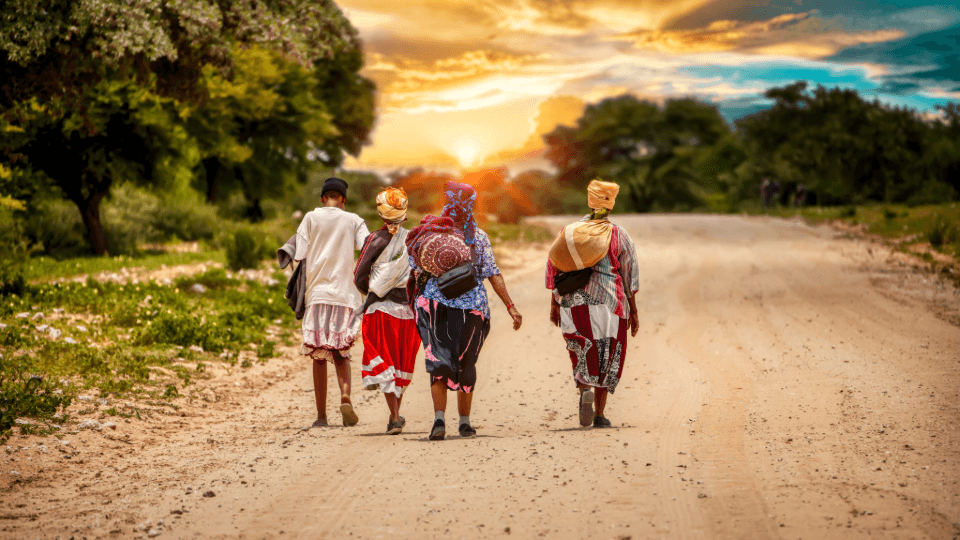 A country road in South Africa, with four people walking toward the setting sun