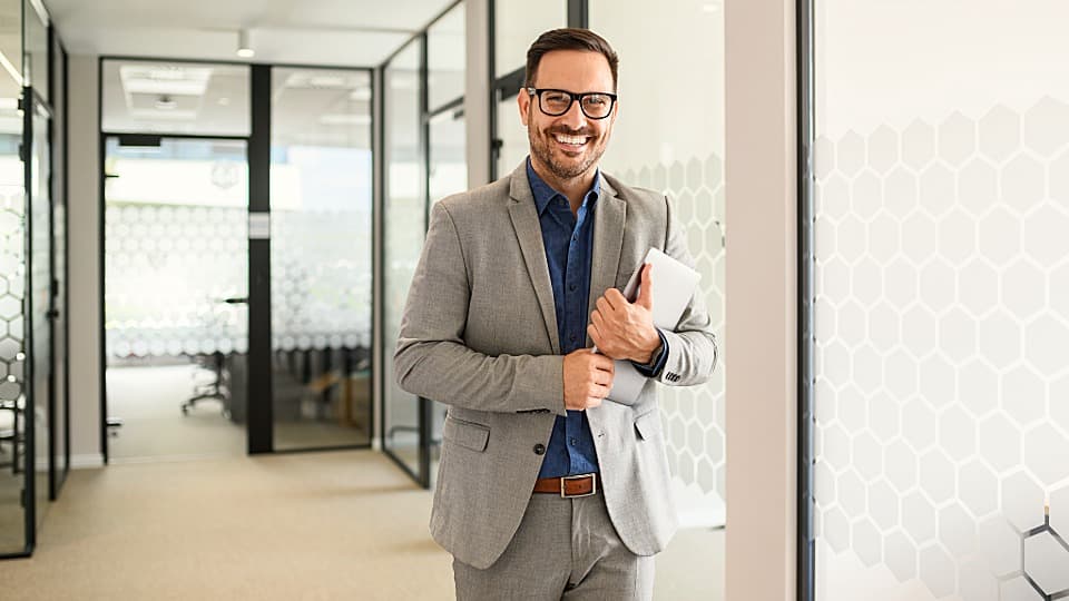 A smiling B2B project manager in a modern office, serving as the dedicated point of contact for your corporate move with DACHSER & KOLB.