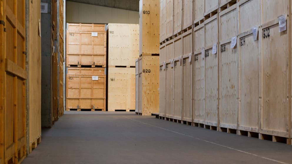 Row of numbered wooden crates in a secured moving warehouse for the safe storage of goods.