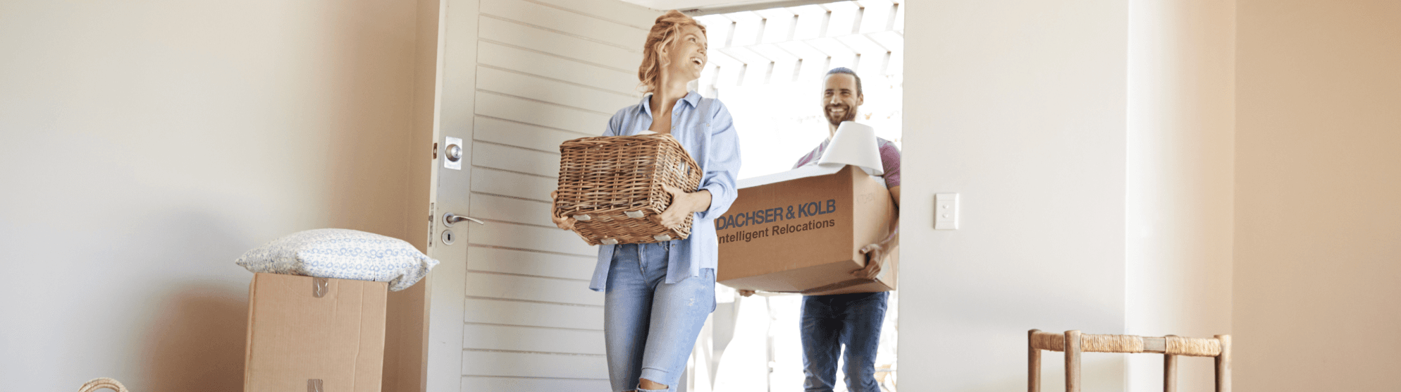 Couple carrying moving boxes and baskets into new home – tips and support in the moving guide