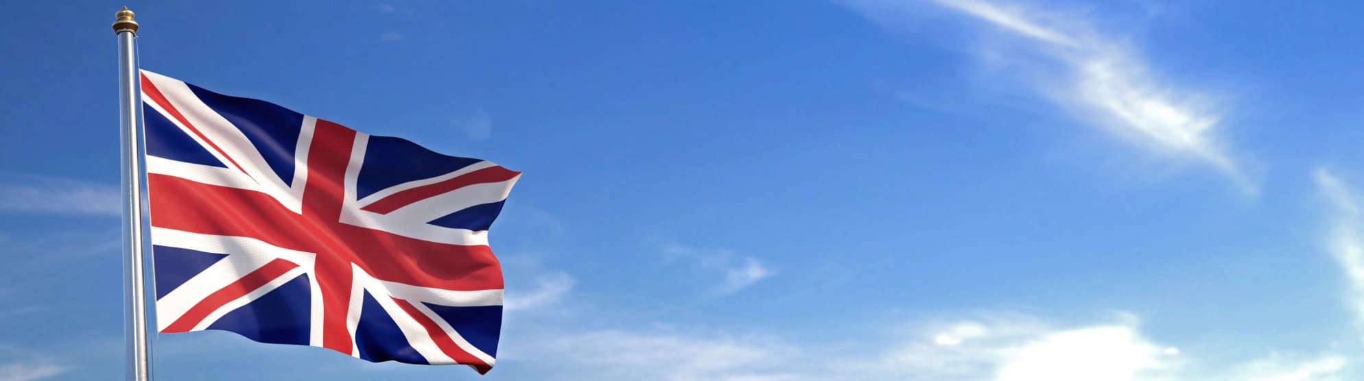 United Kingdom flag (Union Jack) on flagpole against blue sky
