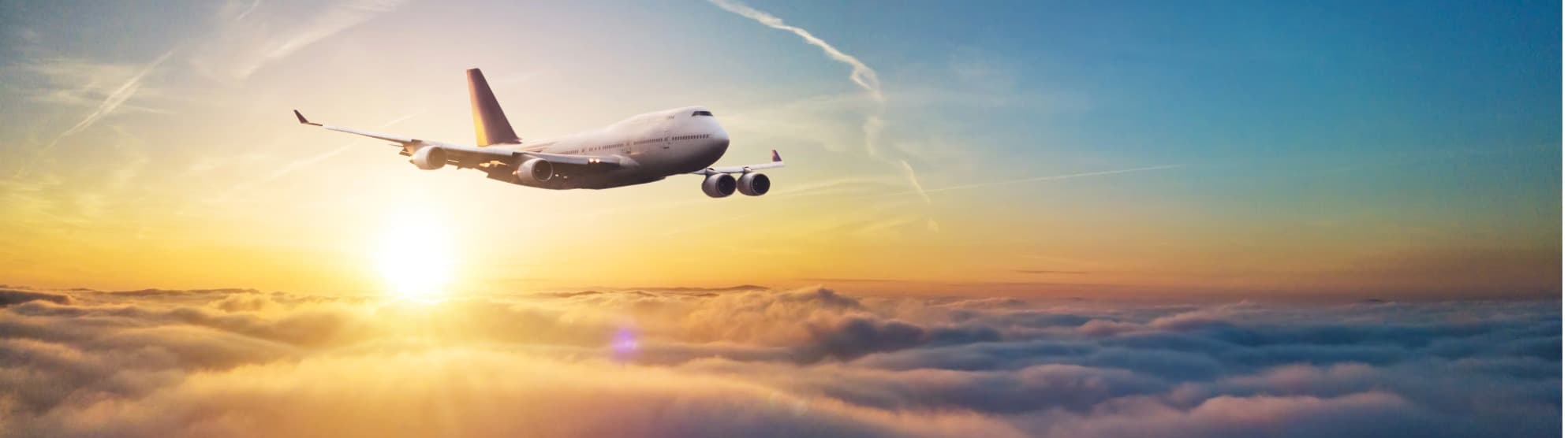 Airline aircraft flying above the clouds at sunrise