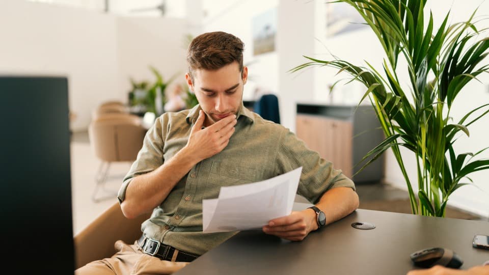 An employee focused on analyzing documents at a desk in a modern office – structuring complex requirements and time-critical logistics workflows.