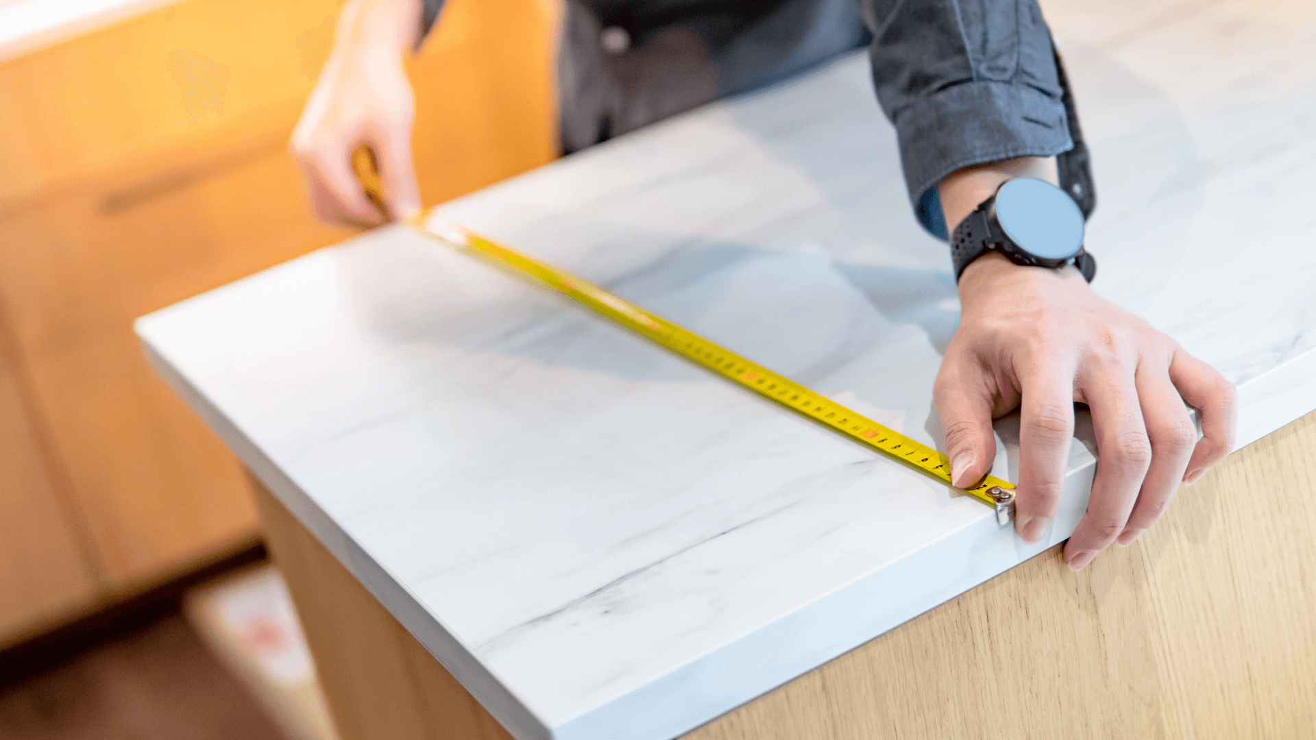 Hand measuring a kitchen countertop with a tape measure to take precise dimensions for kitchen installation.