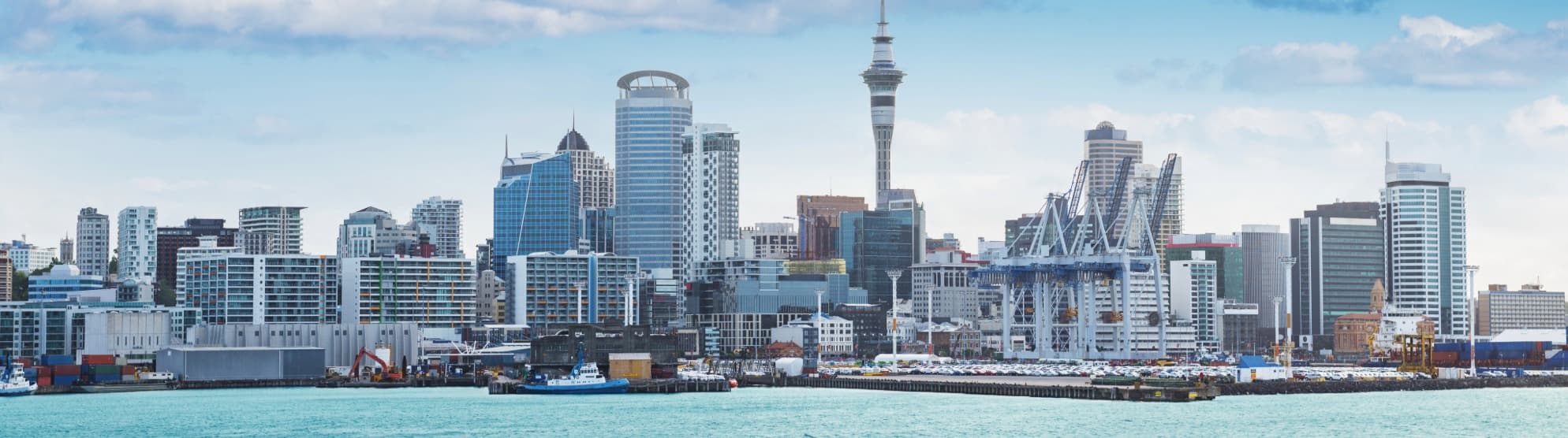 Panorama of the Auckland skyline with the Sky Tower and harbor for a secure overseas relocation to New Zealand with DACHSER & KOLB.