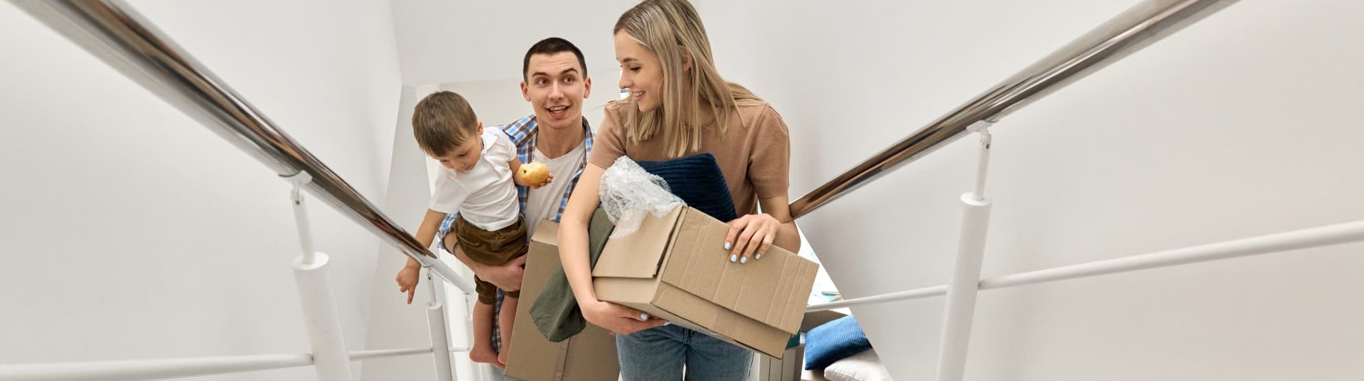 A happy family excitedly carrying moving boxes into their new home during an international relocation with DACHSER & KOLB.