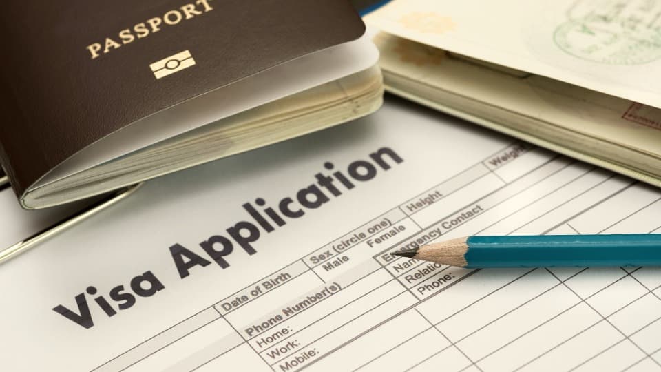 An English visa application form with a passport and a pencil for preparing essential visa and residency documents for an international move with DACHSER & KOLB.