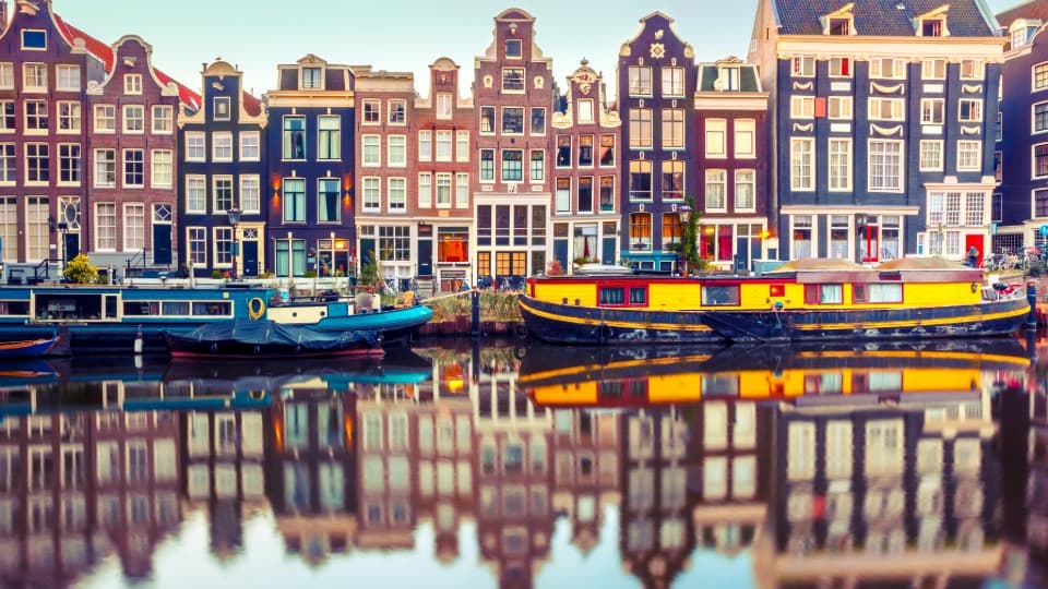 Canal houses and houseboats along a canal in Amsterdam reflected in the water