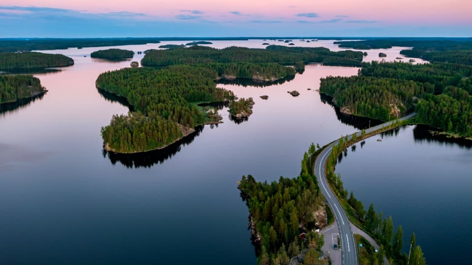 Aerial view of Finland’s lake landscape with islands, forest and a road across the water
