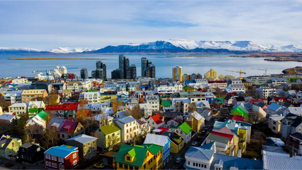 City view of Reykjavík with colourful houses, coastline and snow-covered mountains in the background