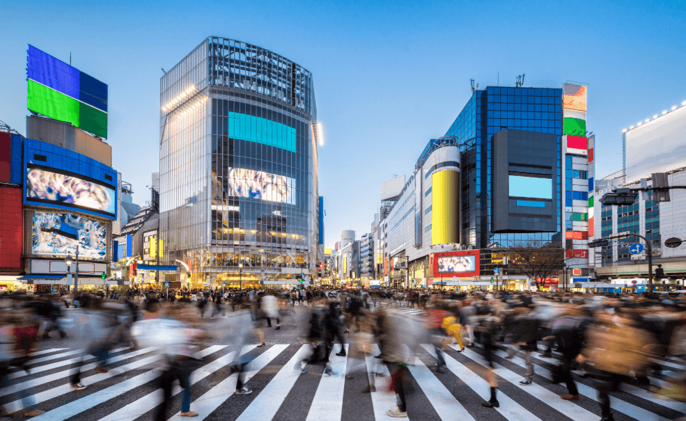 Busy crossing with high-rise buildings and many pedestrians in Tokyo at dusk