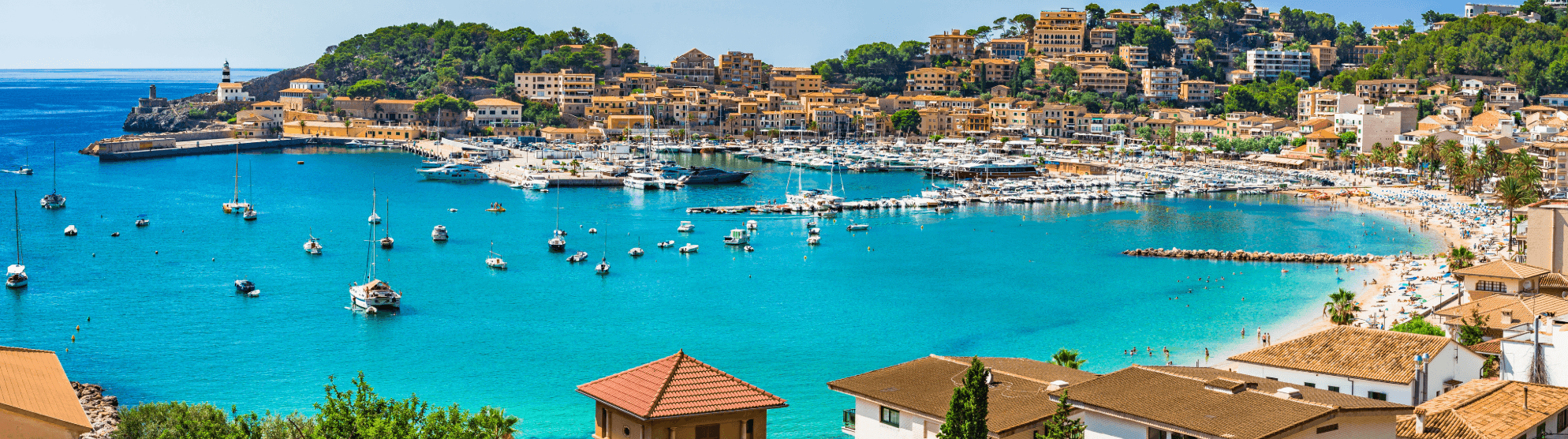 Coastal town in Spain with marina, turquoise bay and beach on a sunny day