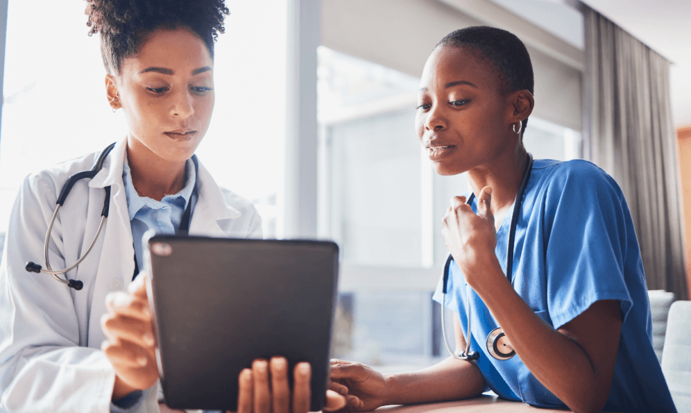 Two female doctors intently reviewing health data on a tablet