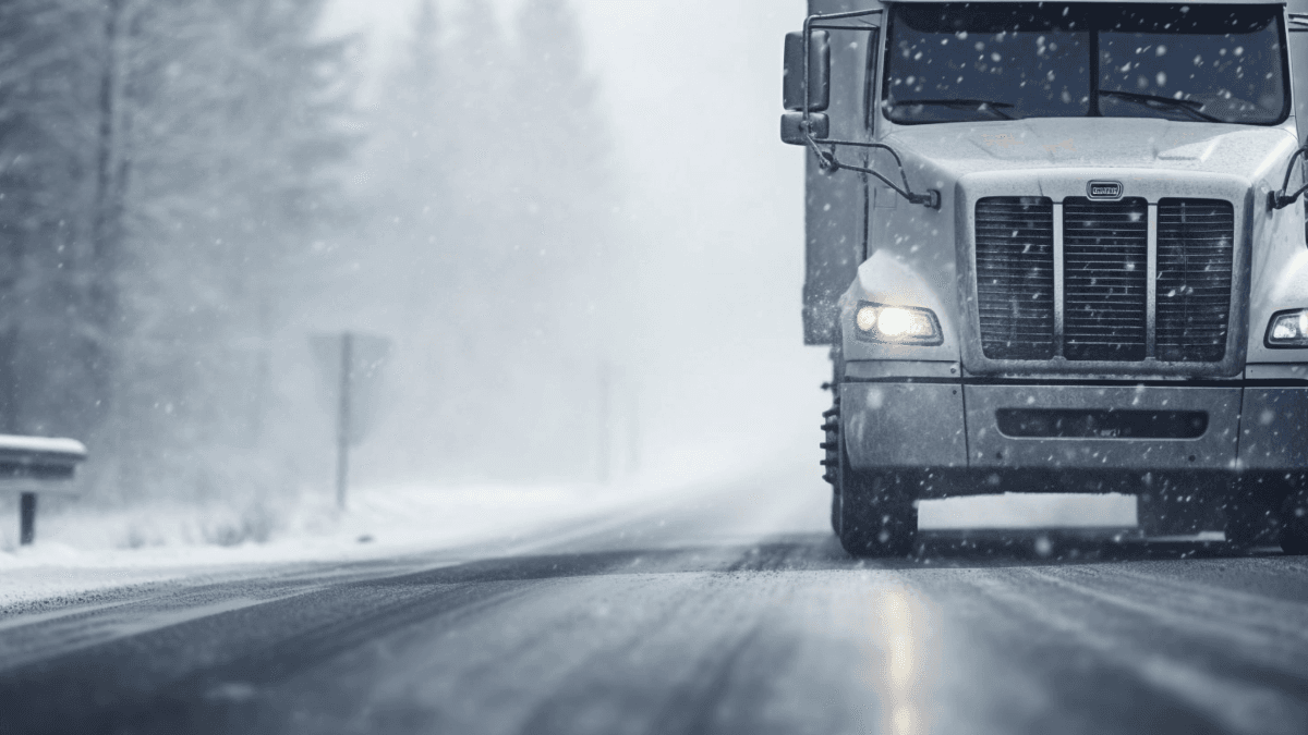 Umzugs-Lkw fährt bei Schneefall auf winterlicher Straße – Umzug im Winter unter schwierigen Wetterbedingungen