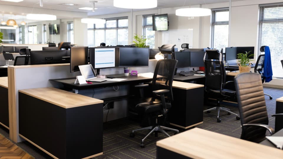 Space optimization during an office relocation – A modern, bright open-plan office with ergonomic desks and computer monitors.