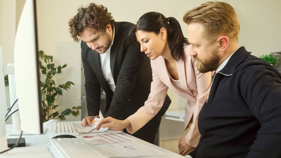A project team jointly analyzing data on a monitor in the office – efficient collaboration, coordinated workflows, and professional management in procurement.