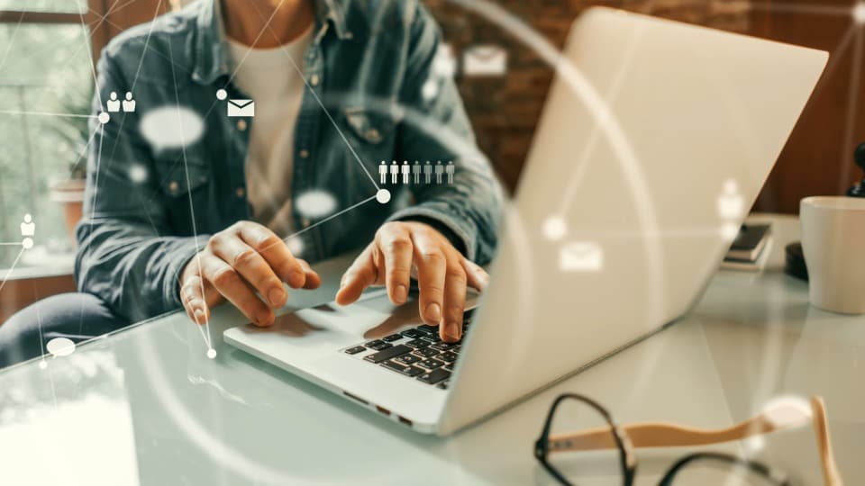 A person working on a laptop with icons for HR networks and workforce capacity – scalability in procurement for worldwide employee relocations.