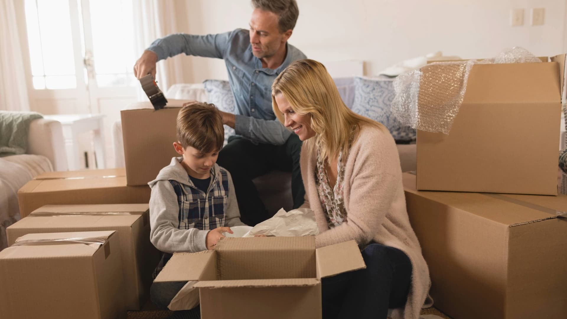 A family unpacking or packing moving boxes in their home. Children help with "Packed by Owner" (PBO) move.