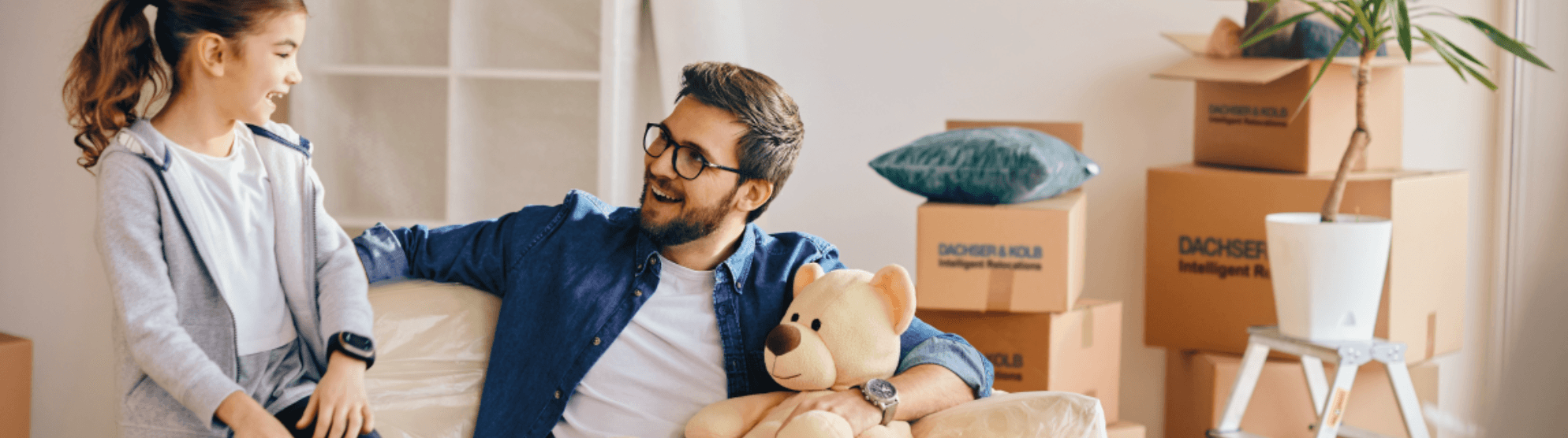 Father and daughter laughing during a move, surrounded by DACHSER & KOLB boxes – Quality with FIDI certification.