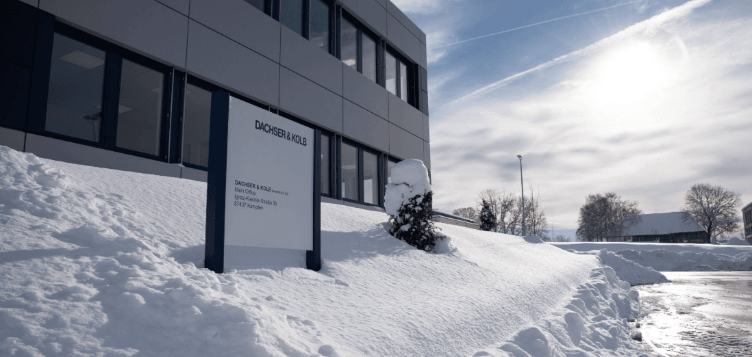 Firmengebäude mit verschneitem Außenbereich beim Umzug im Winter – klarer Himmel und Sonnenlicht im Hintergrund