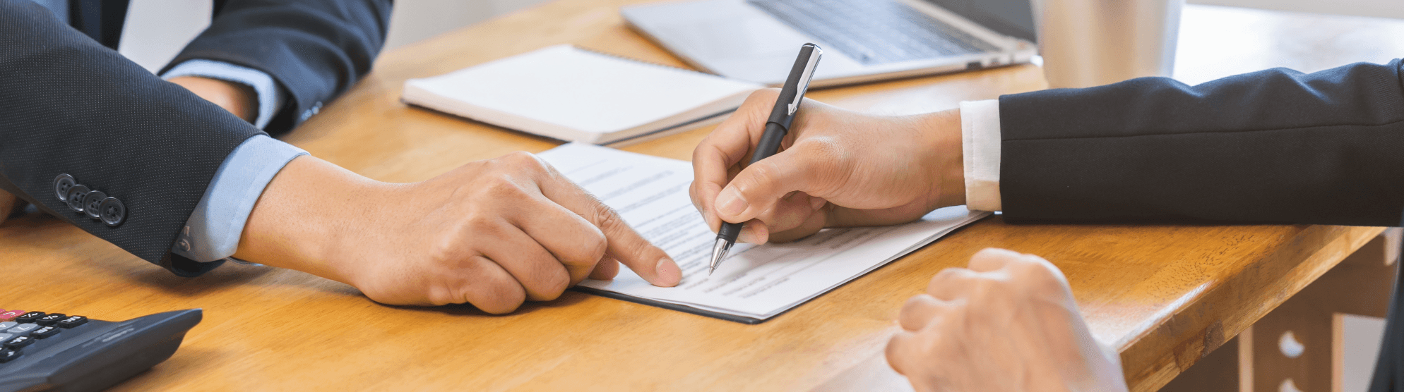 Business people discuss and sign contract focusing on Incoterms. Accessible.