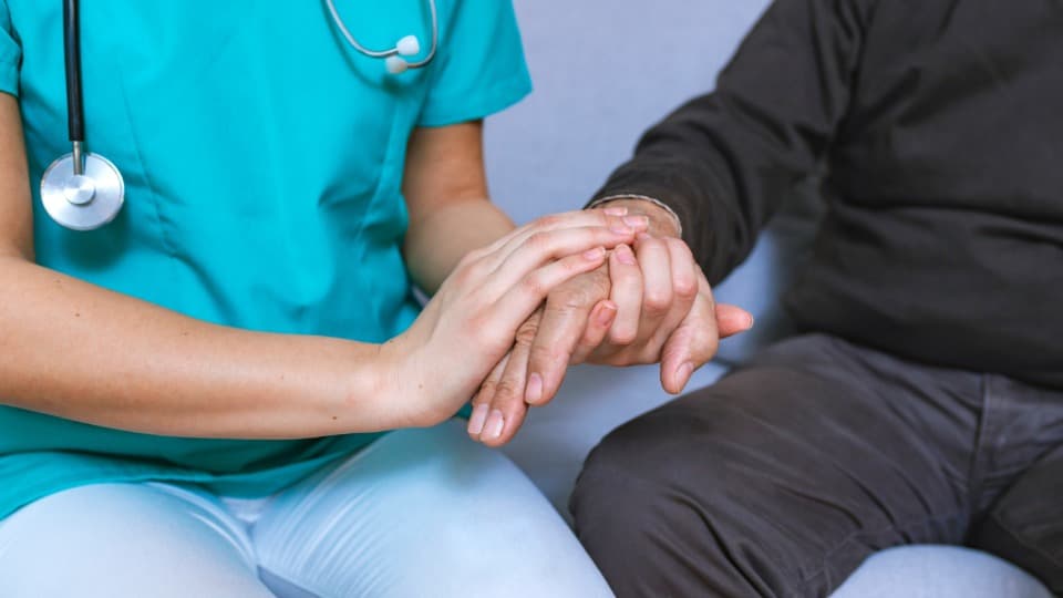 A Romanian doctor holds a patient's hand