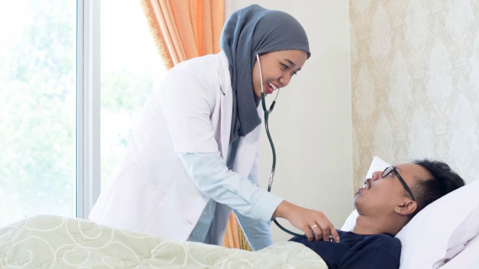 A Malaysian doctor examines a patient with a stethoscope