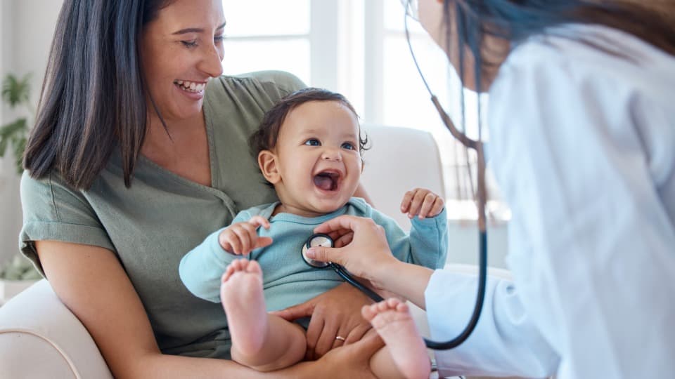 A doctor in Slovakia is examining a child in its mother's arms with a stethoscope