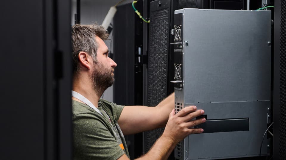 IT relocation with DACHSER & KOLB – An IT logistics specialist pushes a server rack cabinet into place in a data center.
