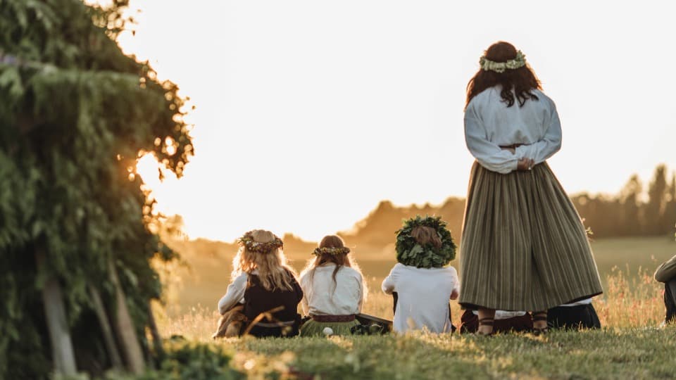 Women and children in Latvian folk costumes wearing flower wreaths at the Jāņi Midsummer celebration – a symbol of Latvia’s deeply rooted culture