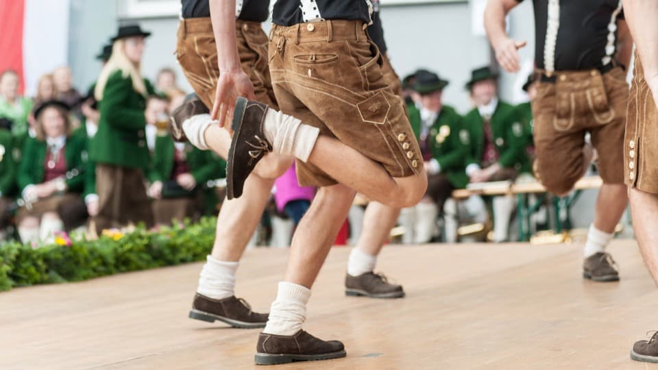 Culture in Austria - Schuhplattler dancers perform on stage, with a brass band visible in the background