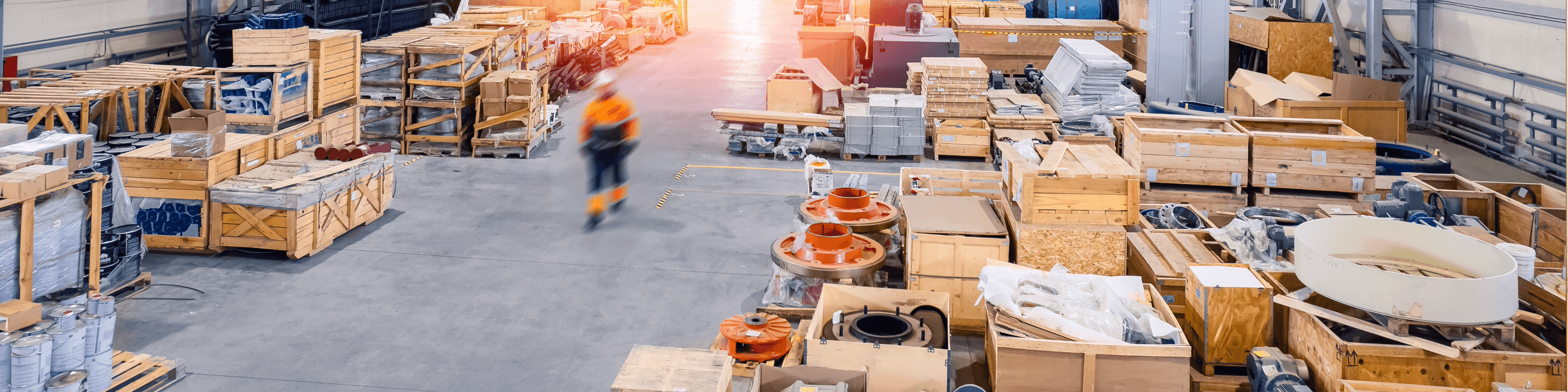 Spacious warehouse with many wooden crates and a worker in motion. Industrial storage and logistics.