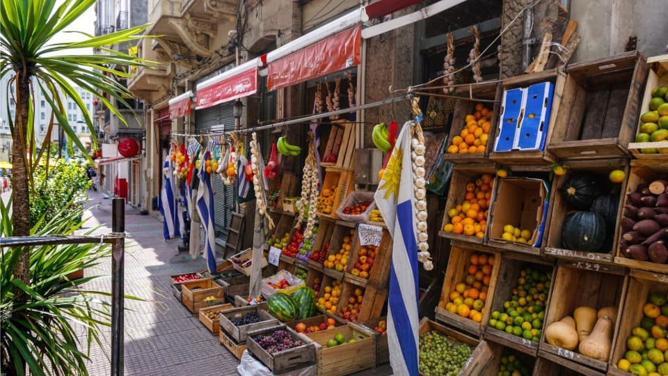 A street lined with shops in Uruguay, with crates of fruits and vegetables set out in front of them