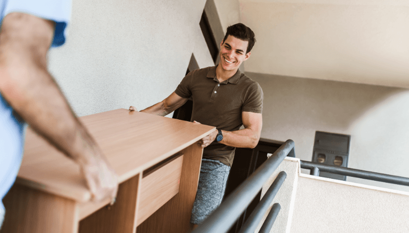 Two men carry furniture during move – follow proper disposal and recycling during relocation