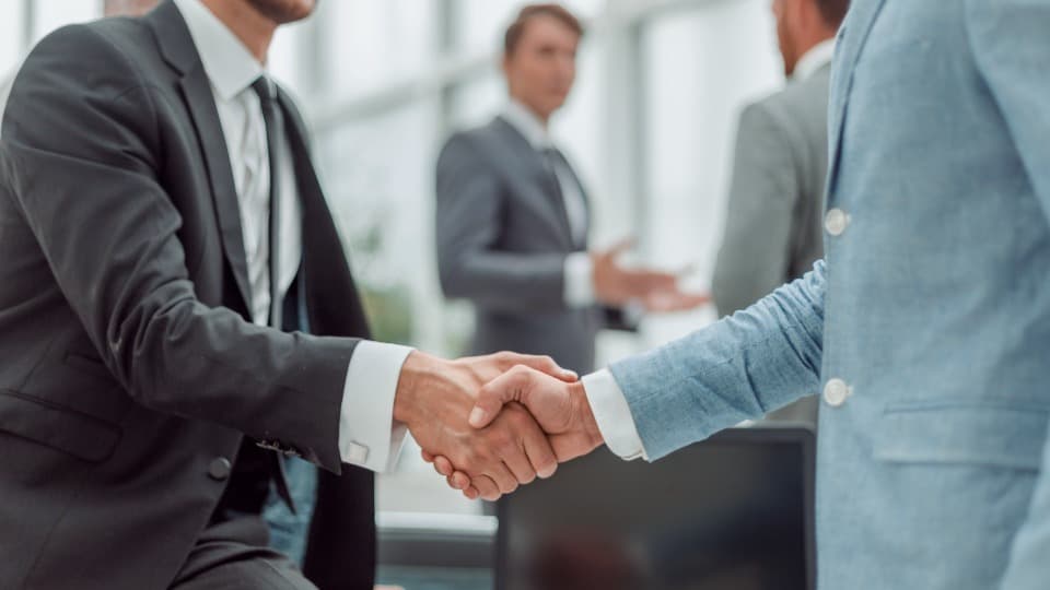 Two business partners sealing a strategic partnership with a handshake – single sourcing and cost optimization for global mobility requirements.