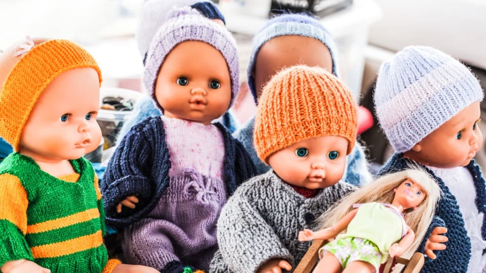Eine Gruppe von Babypuppen in handgestrickter Kleidung zur Veranschaulichung der systematischen Ordnung vor dem Umzug mit DACHSER & KOLB.