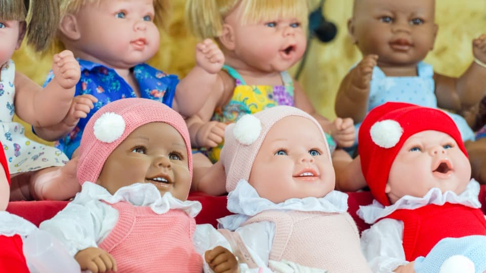 Eine farbenfrohe Gruppe von Babypuppen mit Strickmützen vor der finalen Prüfung der Checkliste für den Umzug mit DACHSER & KOLB.