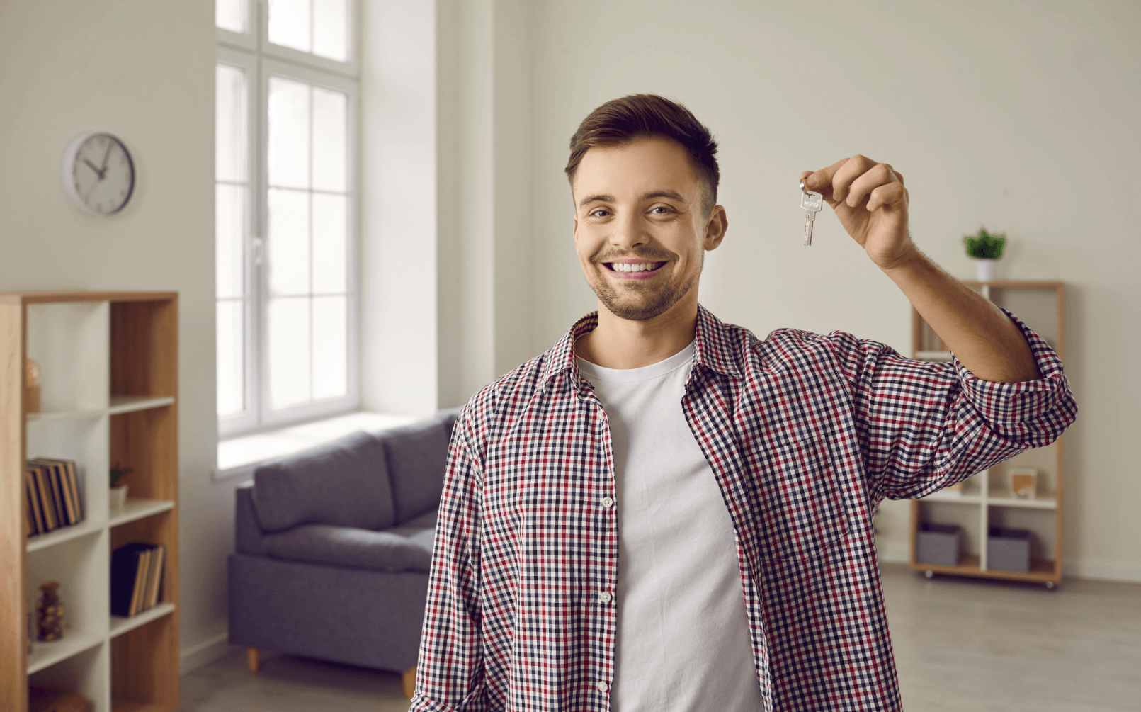Young man holding keys in his new apartment – tips for moving into your first own home