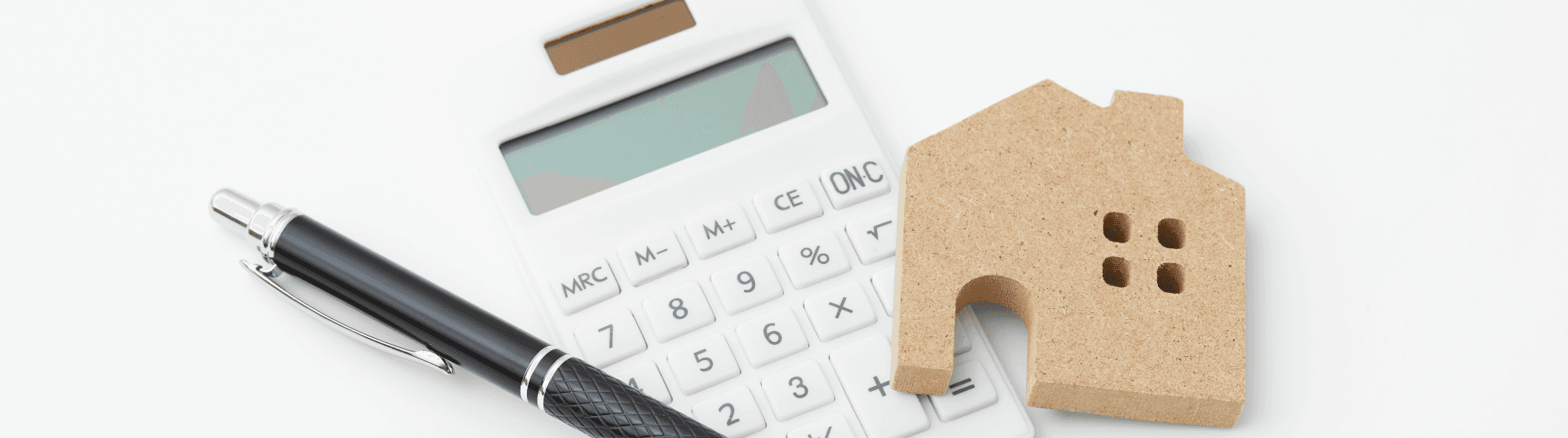 Calculator, pen, and wooden house – symbols for financial planning and tips for calculating moving costs.