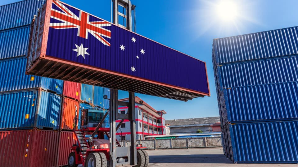 Ein Containerstapler verlädt einen Übersee-Container mit australischer Flagge für den Container-Umzug nach Australien mit DACHSER & KOLB.