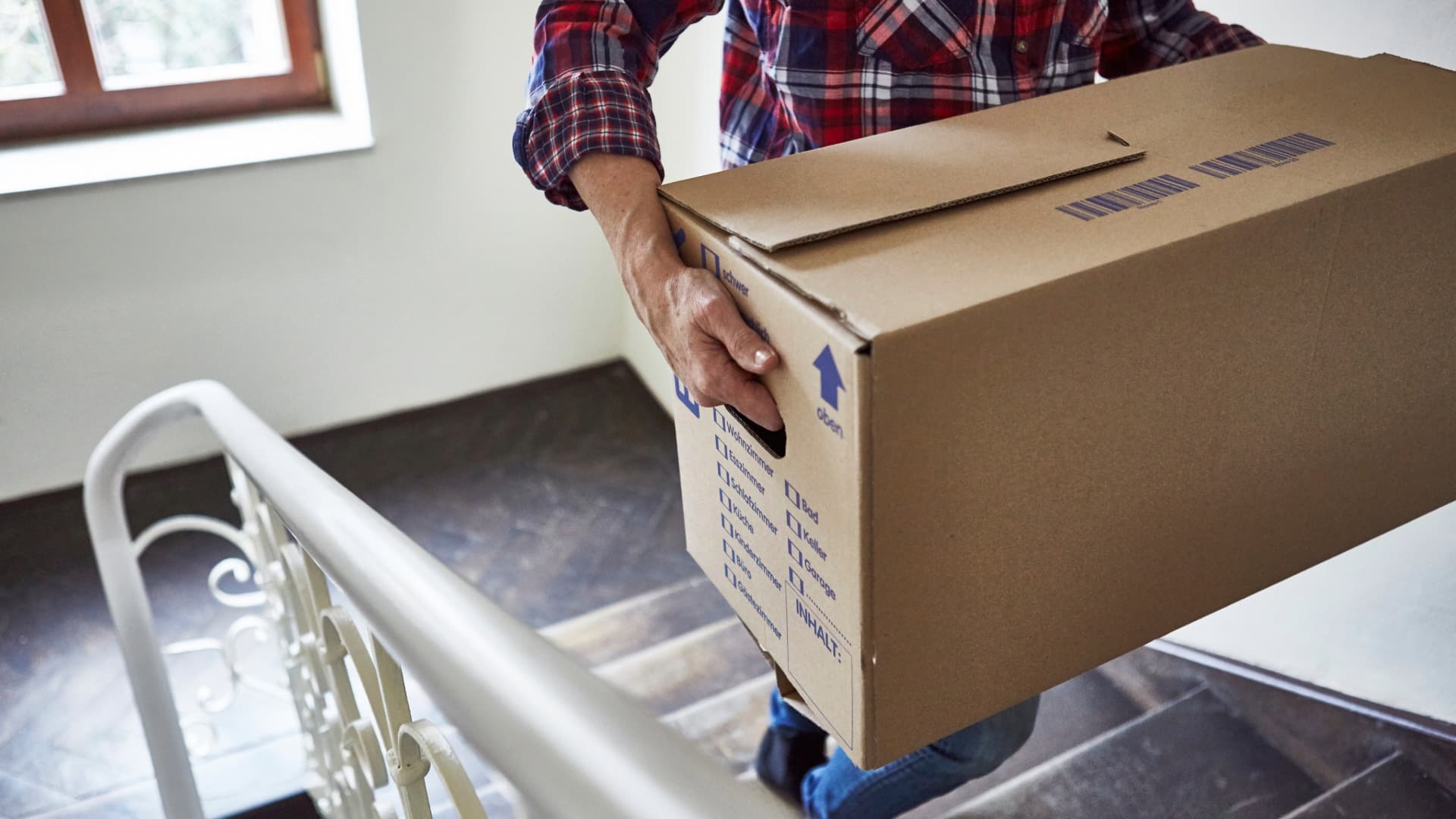 mover carries a moving box in a stairwell – move-in support at destination