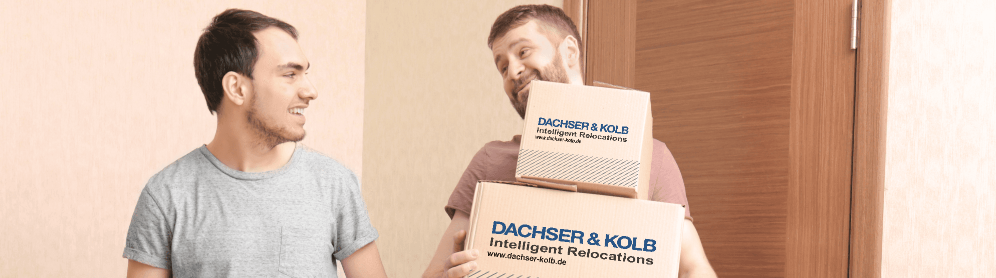 Two men carrying moving boxes with a smile – a good example of how to pack and carry moving boxes correctly.